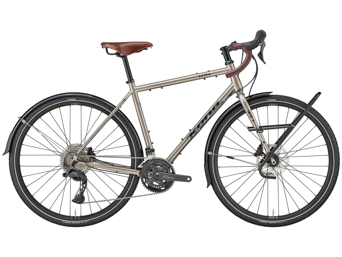 Vélo de cyclotourisme Kona Sutra en acier, coloris Gloss Metallic Nickel, vue latérale complète montrant le cadre Cromoly, les garde-boue complets et le porte-bagages avant Tubus.