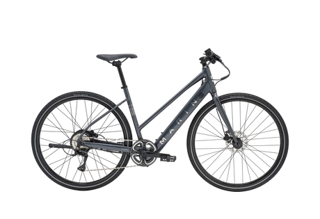 Vélo hybride électrique urbain Marin Fairfax Electric ST 2026 à cadre ouvert, coloris Charcoal, vue latérale complète montrant le cadre Series 1 en aluminium, la batterie intégrée au tube diagonal et les pneus Vee Tire City Cruz 700x40c.
