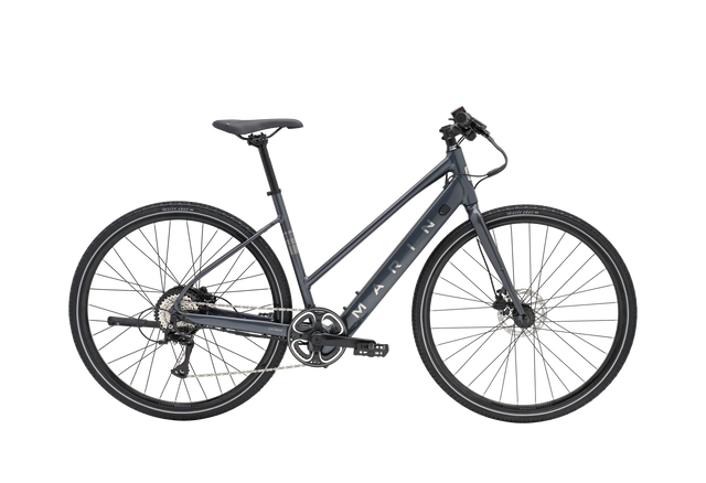 Vélo hybride électrique urbain Marin Fairfax Electric ST 2026 à cadre ouvert, coloris Charcoal, vue latérale complète montrant le cadre Series 1 en aluminium, la batterie intégrée au tube diagonal et les pneus Vee Tire City Cruz 700x40c.