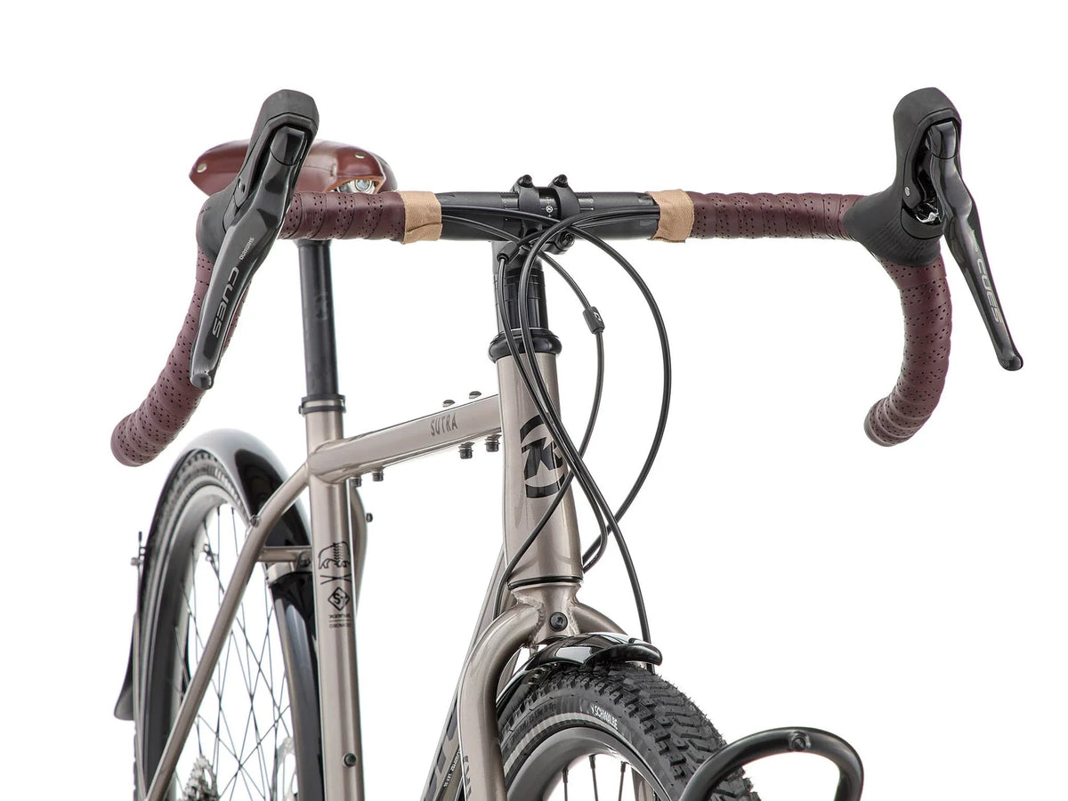 Détail du poste de pilotage du Kona Sutra : cintre gravel Kona, poignées Brooks microfibre et commandes intégrées Shimano CUES à portée de main.