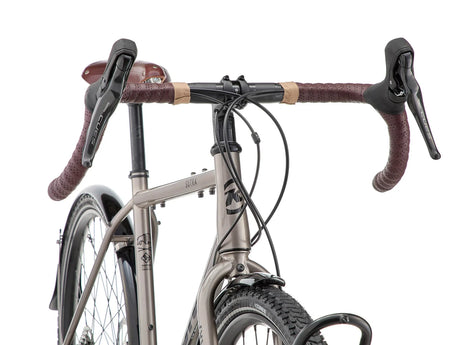 Détail du poste de pilotage du Kona Sutra : cintre gravel Kona, poignées Brooks microfibre et commandes intégrées Shimano CUES à portée de main.
